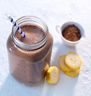 Banana Chocolate Smoothie made with Astro Yogurt served in a mason jar with a blue-striped straw.