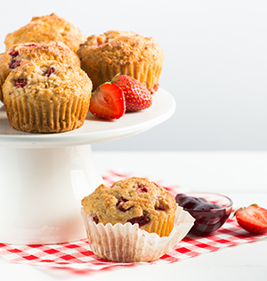 Honeyed Strawberry Yogurt Muffins made with Astro yogurt on a white plate with strawberries on the side