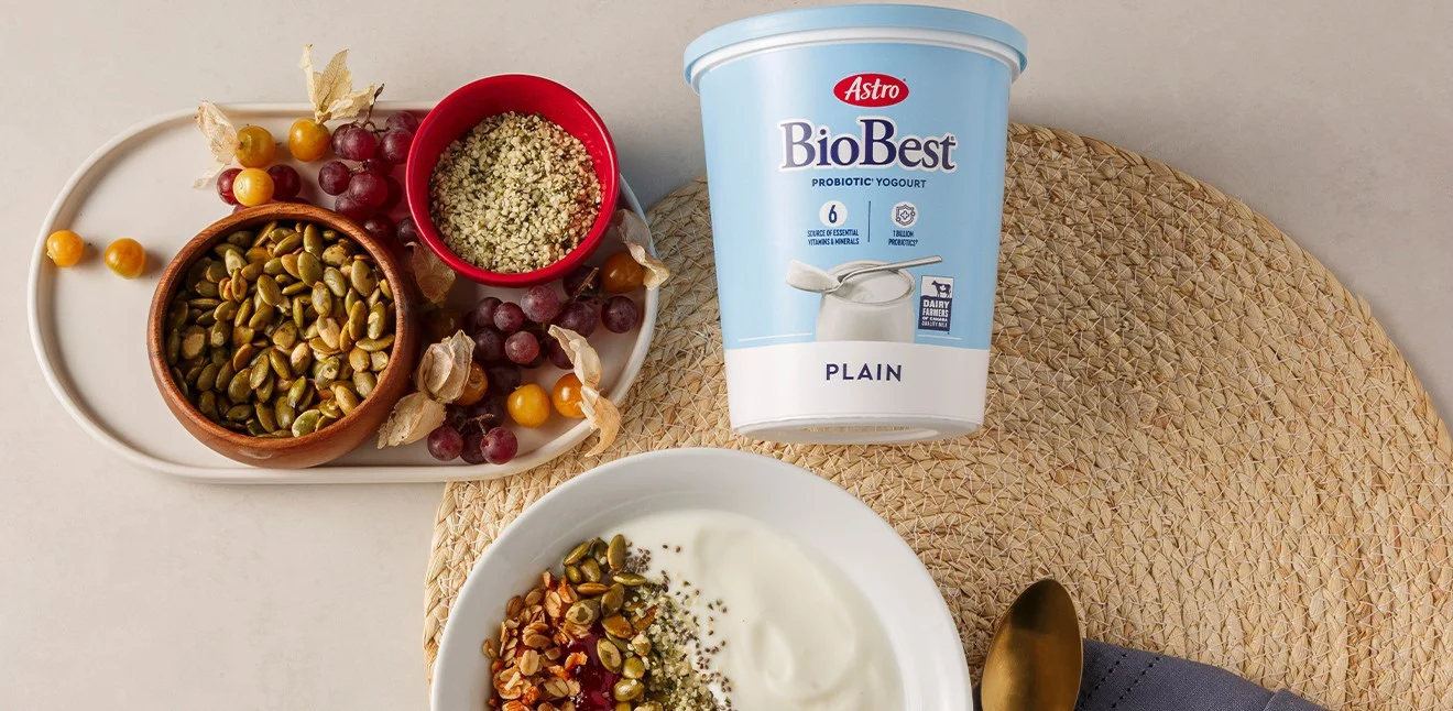 Biobest tub on a table with various grains. A bowl of yogurt with grains added. Assorted fruit
