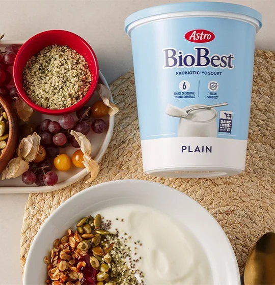 Biobest tub on a table with various grains. A bowl of yogurt with grains added. Assorted fruit