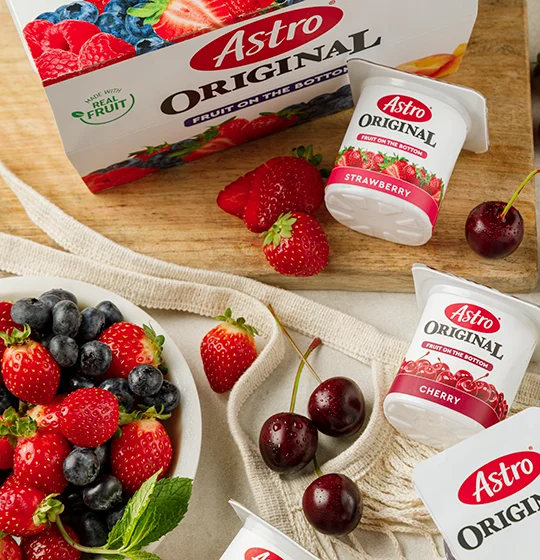 Fruit on the bottom small tubs on a table with various fruit and a bowl of fruit on a table