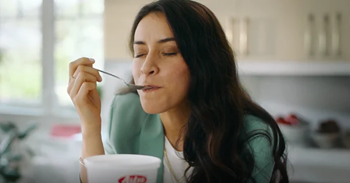 Lady eating a spoonful of Astro yogurt in the kitchen