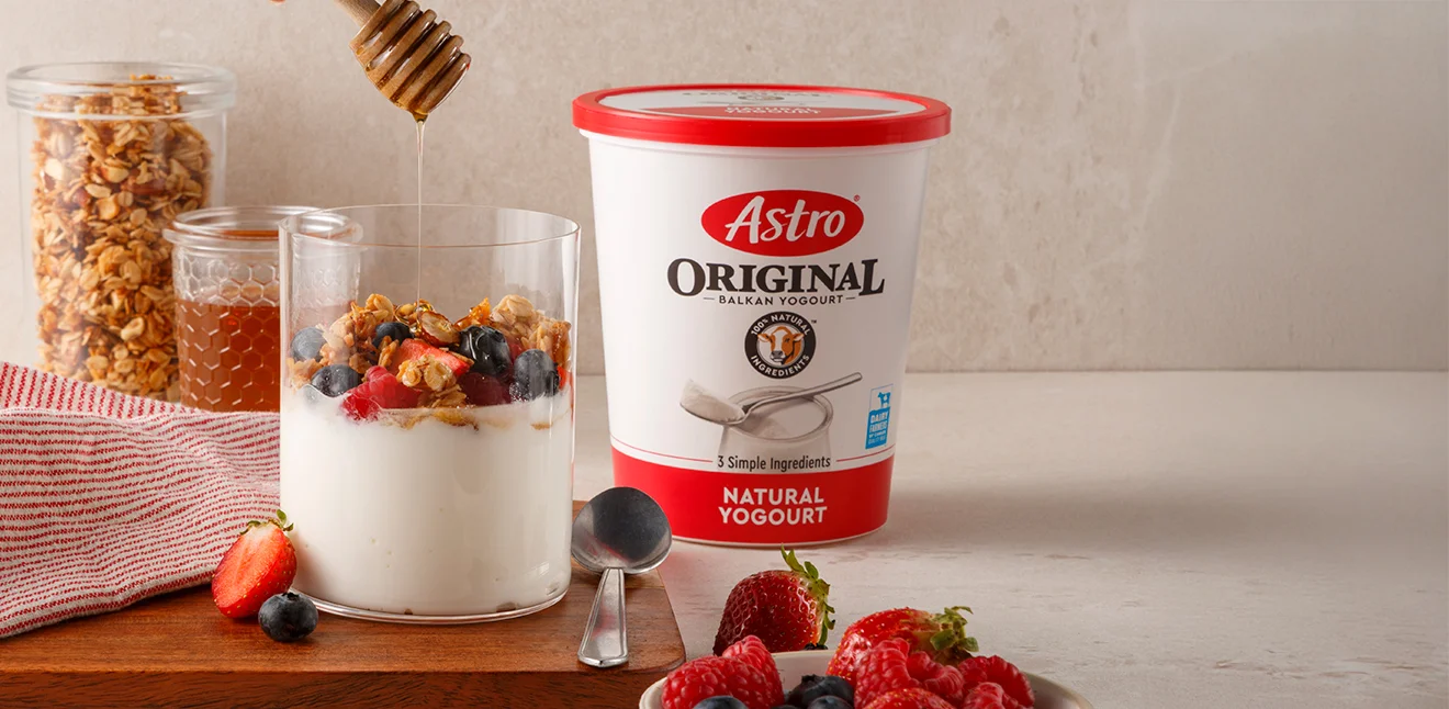 Plains 6% tub on a table width yogurt in a cup with honey, fruit and grains